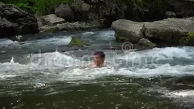 那家伙正在河里游泳。 一个年轻可爱的家伙在一条干净的山河里洗澡。 他很开心。