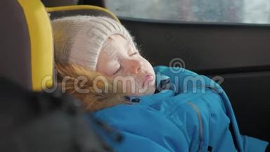 幼儿男孩在汽车上睡在儿童安全座椅上。