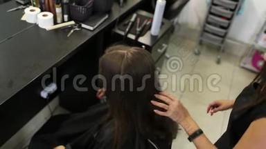 一个女人在发廊把头发弄直的特写镜头。 在缓慢的运动中卷曲铁射击。 高清高清