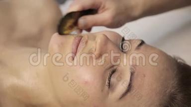 美丽的女人有一个穴位按压的脸与刮刀沟。 中国替代疗法