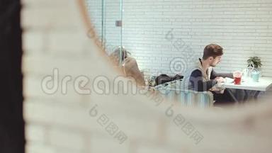 有智能手机的年轻人坐在镜子里的咖啡馆里