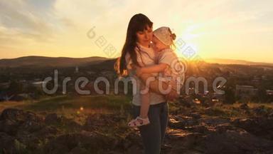 一个幸福的家庭在日落时，母亲抱着她的女儿在<strong>怀里</strong>。