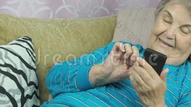 躺在米色沙发上的老妇人拿着手机