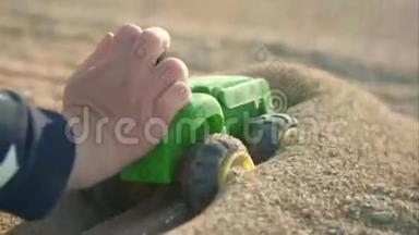 一辆玩具<strong>绿色卡</strong>车在沙滩上行驶。