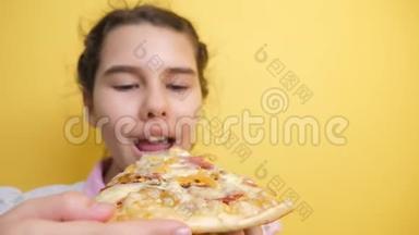 快乐的小女孩吃一片披萨的概念。 十几岁的孩子饿了吃一片披萨。 慢动作视频。 披萨饼