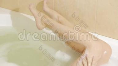 女人用泡沫享受愉快的沐浴，用一缕水洗腿
