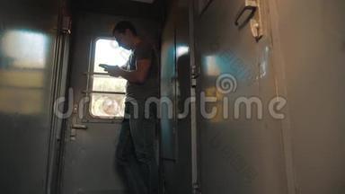 那个人的轮廓站在<strong>火车车厢</strong>上，手里拿着一部智能手机。 慢动作视频。 男人写字