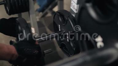 帅哥健美运动员准备在健身房用杠铃做运动，把杠铃牌放在健身房里