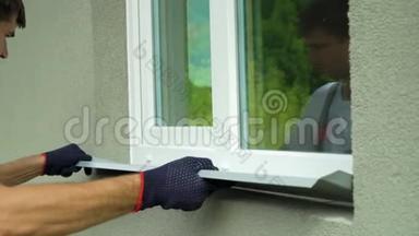 测量外部框架和PVC窗台尺寸的防护手套工人