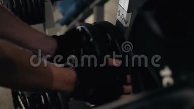 帅哥健美运动员准备在健身房用杠铃做运动，把杠铃牌放在健身房里
