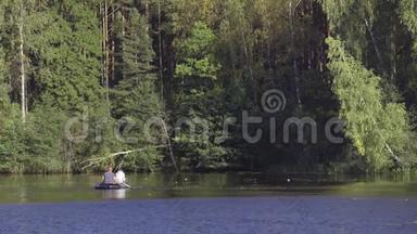 两个穿着橡皮船的渔夫在河上划桨。 人在阳光明媚的森林里湖上钓鱼。 斯特拉克河-