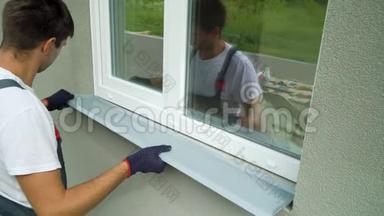 测量外部框架和PVC窗台尺寸的防护手套工人