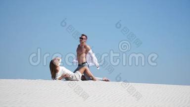 一个强壮的男人和一个美丽的女孩躺在沙漠的沙滩上