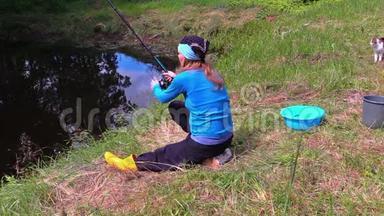 女孩在池塘里扔棍子，在岸上钓鱼。 塔比猫走来走去。