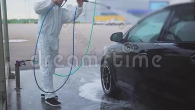 那个人用喷水器洗车。洗车自助服务。