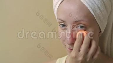 年轻漂亮的女人在浴室里用遮瑕膏