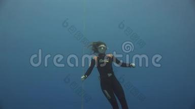 水下模型自由潜水员用红色浮标在红海干净的蓝色水中游泳。