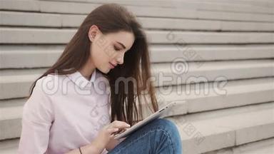 年轻漂亮的学生女孩在外面用平板电脑。 很漂亮的少女在空中看书。