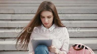 年轻漂亮的学生女孩在外面用平板电脑。 很漂亮的少女在空中看书。