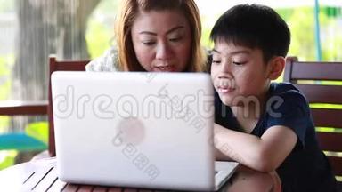 年轻快乐的母亲带着孩子在<strong>露台</strong>上使用笔记本电脑