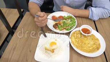 泰国菜-米饭，煎蛋卷，蔬菜和猪肉。 一个男人在餐馆吃泰国菜。 4k，慢动作