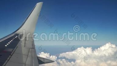 <strong>飞机</strong>正通过白云在蓝天上飞行。 从窗户看到<strong>飞机机翼</strong>。 旅行和
