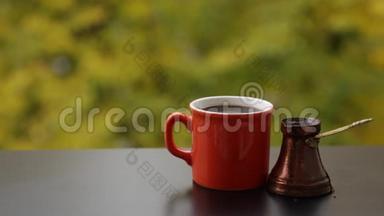 用传统土耳其壶冲泡的红色咖啡杯中的美味热咖啡，户外咖啡桌