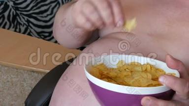 胖，懒汉正坐在椅子上吃薯片.. 男人的大肚子.. 快餐，不是健康食品