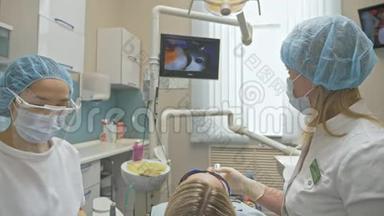 医生用特殊的口腔内检查数字微型相机检查牙齿。 监控牙医和病人看录像