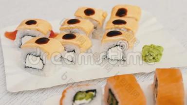 美味的寿司，三文鱼，奶酪，芥末，粉红色生姜，酱油在时尚的白色木制背景上。