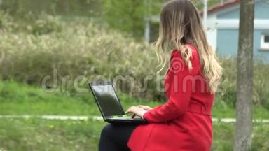 穿红裙子的女孩拿着笔记本电脑在街上工作