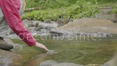 年轻女子摸着<strong>森林</strong>里的河水。 年轻的<strong>游客</strong>触摸河流
