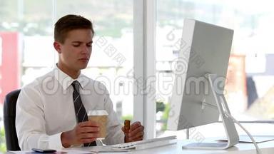年轻的商人在电脑工作时吃喝