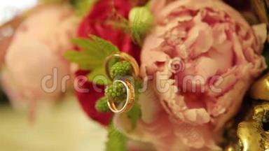 结婚戒指和粉红色玫瑰花束。 婚礼花束上的结婚戒指。 玫瑰花束上的结婚戒指。