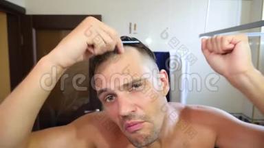年轻有魅力的男人在浴室里检查一条后退的发际线。 秃头。 4k，慢动作