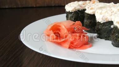 一个白色的<strong>大盘</strong>子，上面放着四个巨大的寿司黑吉里，旁边是粉红色的生姜和绿色的芥末