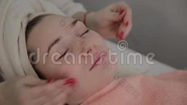 一位专业的美容师在敷面膜之前做面部按摩。 美容学的新概念。