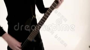 年轻的男音乐家穿着黑色衣服，白色<strong>背景</strong>上有一把黑色低音吉他。 低音吉他<strong>演奏</strong>者<strong>演奏</strong>音乐