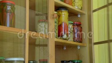 女孩用手把罐装的玻璃罐放到食品储藏架上