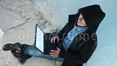 黑客攻击服务器。 在冰洞里用笔记本电脑编程。 围绕着神秘的冰窟.. 男人把自己藏在