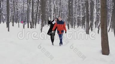 一对年轻的夫妇在冬季森林里慢动作散步