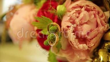 结婚戒指和粉红色玫瑰花束。 婚礼花束上的结婚戒指。 玫瑰花束上的结婚戒指。