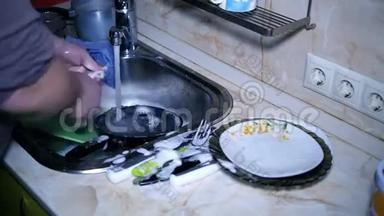厨房里的人在洗碗池里快速地刷洗碗碟