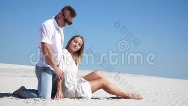 可爱的夫妇坐在沙漠里的沙滩上