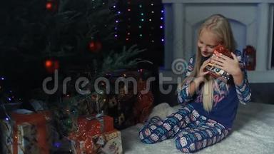 一个小女孩坐在圣诞树下，正在考虑礼物