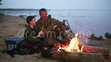 父子俩围坐在湖边的篝火旁..