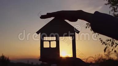 太阳落山时，特写双手握住房子。