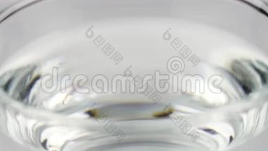 黄色泡腾片止痛片落入玻璃杯中，在彩色片上溶解慢镜头的阿司匹林