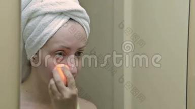 年轻漂亮的女人在浴室里用遮瑕膏