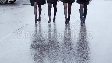 四个穿着高跟<strong>鞋</strong>的女人的腿在<strong>潮</strong>湿的沥青上紧紧地走着。 慢动作